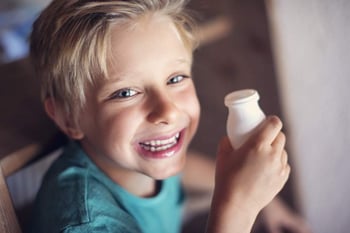 Child with drinkable container of yogurt