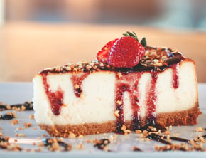 strawberries and chocolate drizzle on top of a cheescake