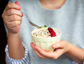 person eating yogurt with a strawberry on top